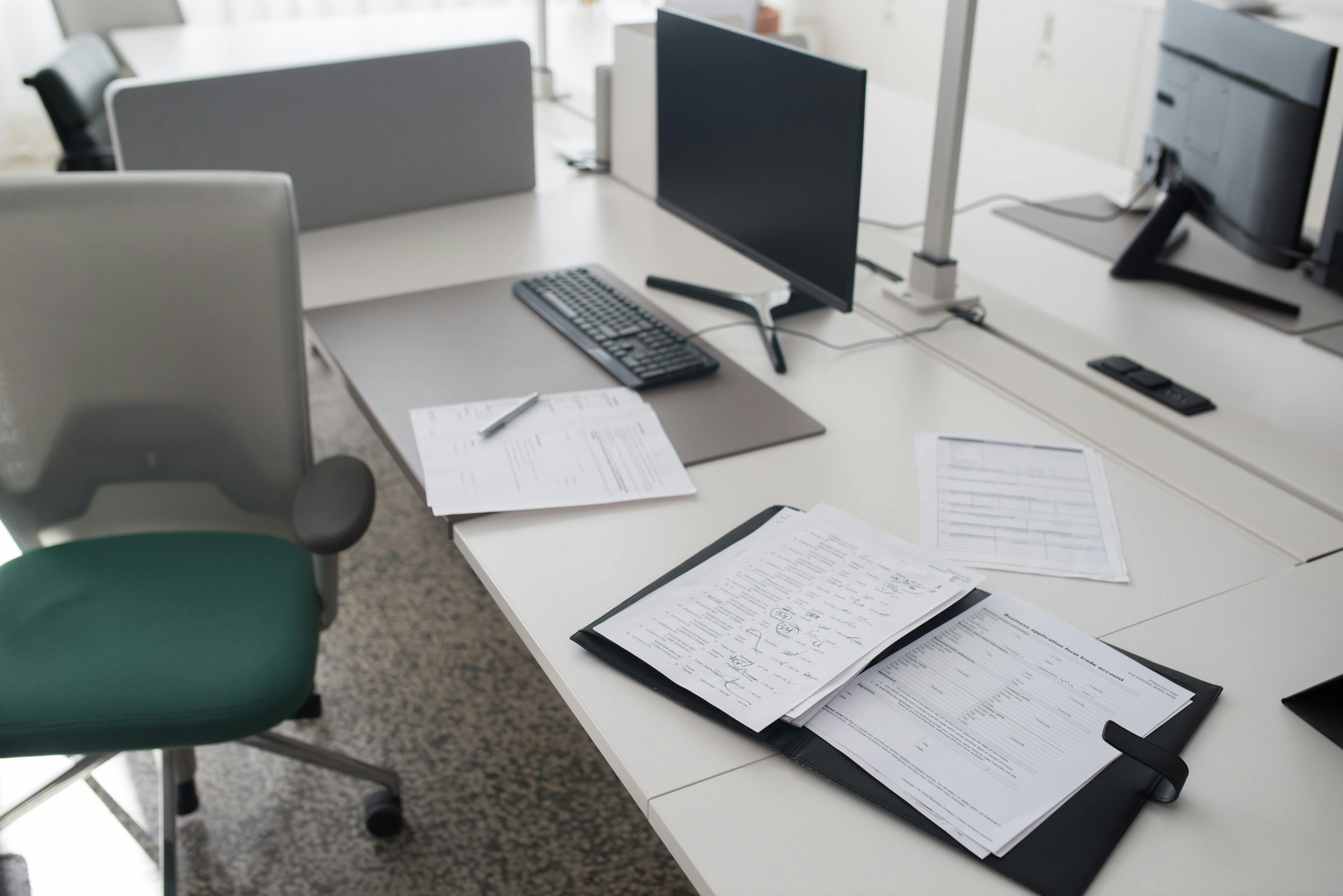 A clean and organized office desk with documents, a computer, and chair in a modern workspace.